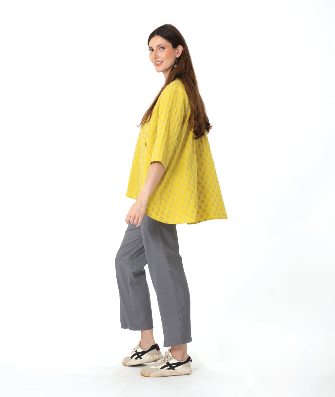 model in a yellow two tone checker board print button down blouse with 3/4 sleeves and a full body. worn with a slim grey pant