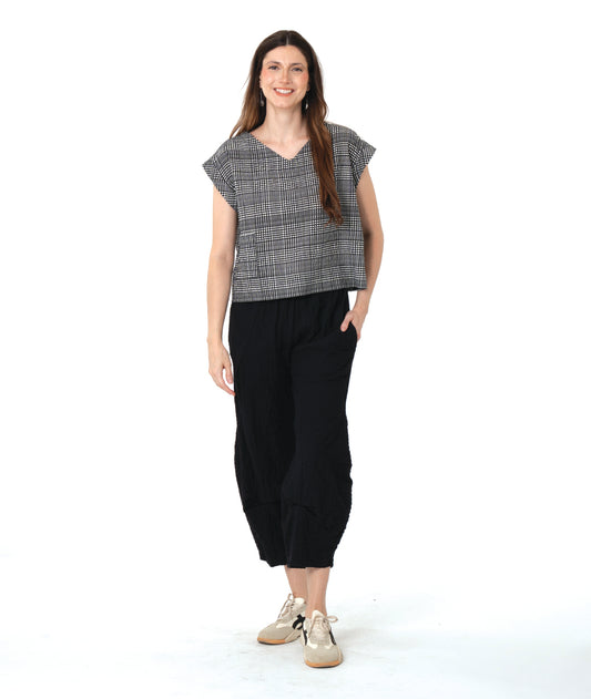 model in a checker print pullover boxy top with a black pant with an elastic waist and tucks at the center front legs