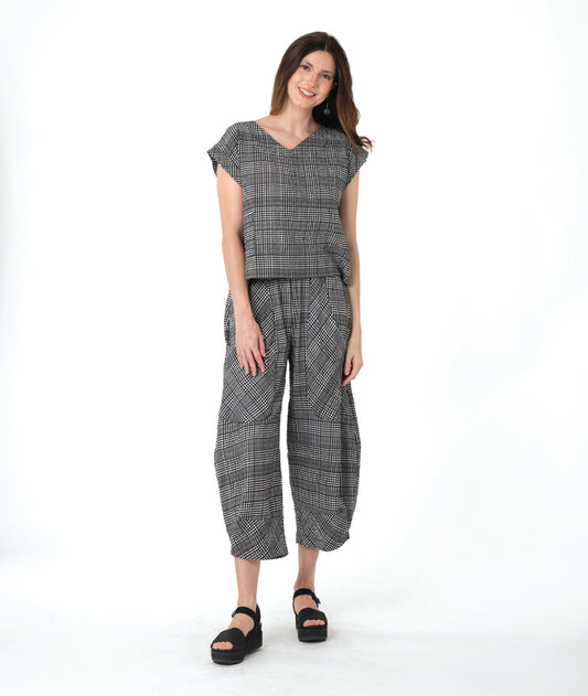 model in a black, white and grey plaid pair of pants with oversized contrasting pockets, wide legs and a tapered ankle. worn with a matching boxy pullover top