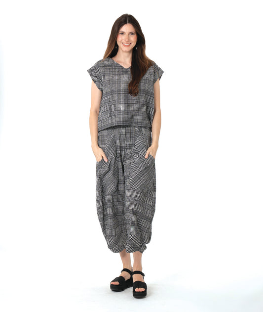 model in a black, white and grey plaid pair of pants with oversized contrasting pockets, wide legs and a tapered ankle. worn with a matching boxy pullover top