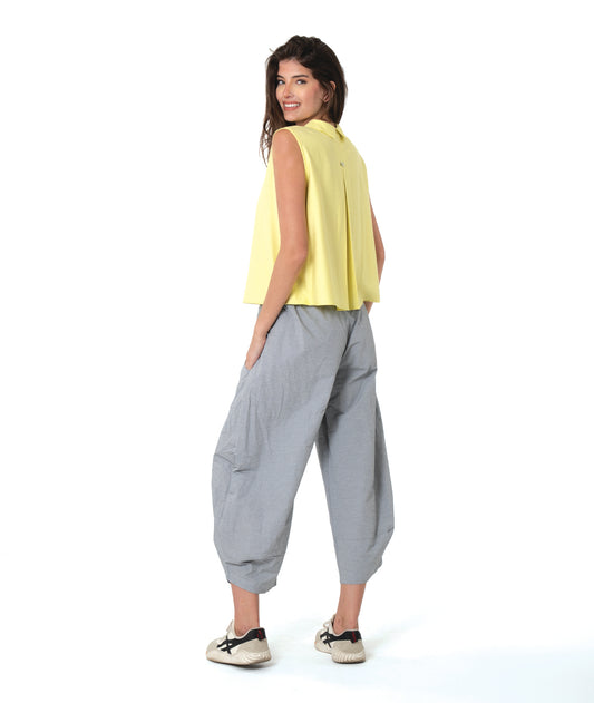 model in a wide leg grey and white striped pant with a tapered ankle, worn with a soft yellow sleeveless button down blouse with a twin button detail