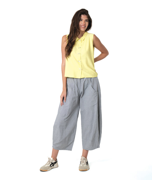 model in a wide leg grey and white striped pant with a tapered ankle, worn with a soft yellow sleeveless button down blouse with a twin button detail