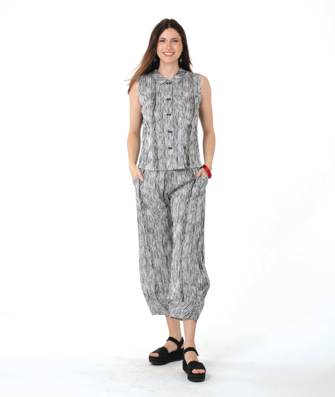 model in a wide leg black and white striped pant with a tapered ankle, worn with a matching sleeveless button down blouse