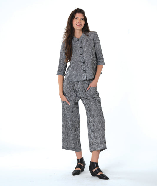 model in black and white striped pants with asymmetrical cargo pockets and a matching button down blouse