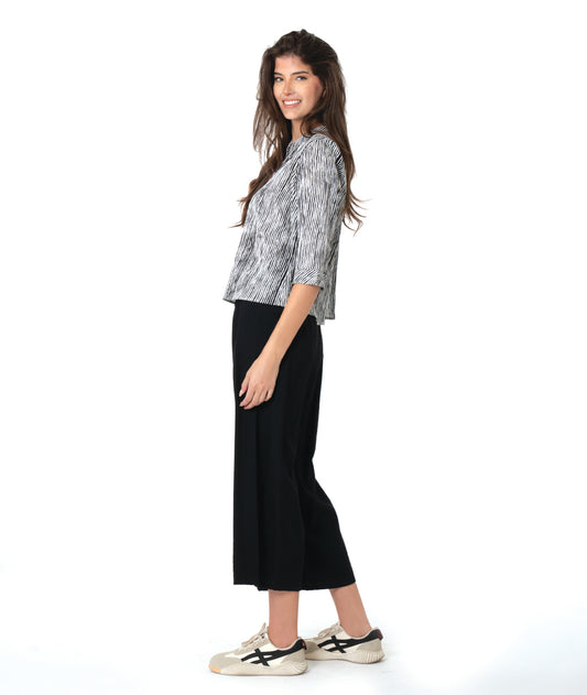 model in a wide leg black pant with a split at the ankle front, worn with a black and white striped blouse with 3/4 sleeves and a twin button detail