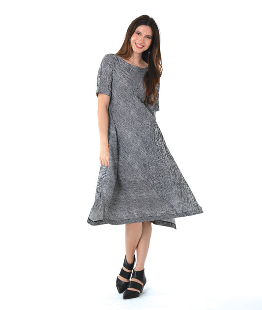 model in a black and white striped dress with contrasting panels of directional stripes. Dress has a round neckline, elbow length sleeves and splits and tucks at the sides