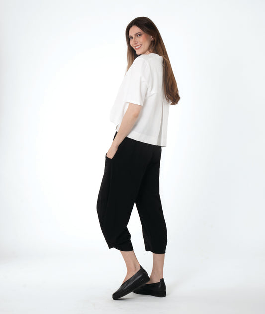 model in a cropped black pant with a boxy button down with an elbow length sleeve and an open collar