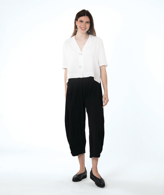 model in a cropped black pant with a boxy button down with an elbow length sleeve and an open collar