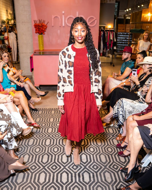 model in a red dress and leopard print cardigan walking down runway