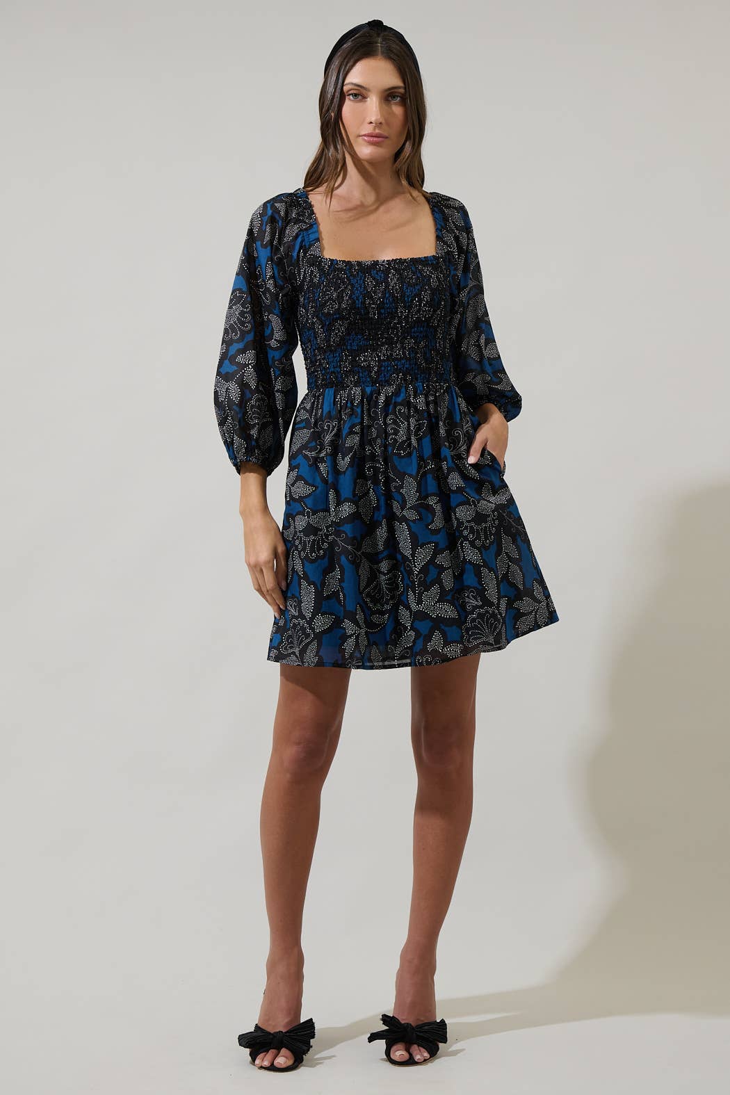 Woman wearing a patterned dress on a plain background