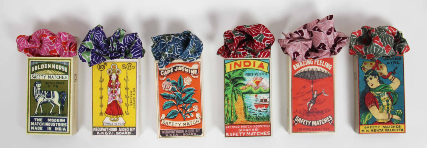 Collection of vintage matchboxes with colorful labels and decorative ribbons.