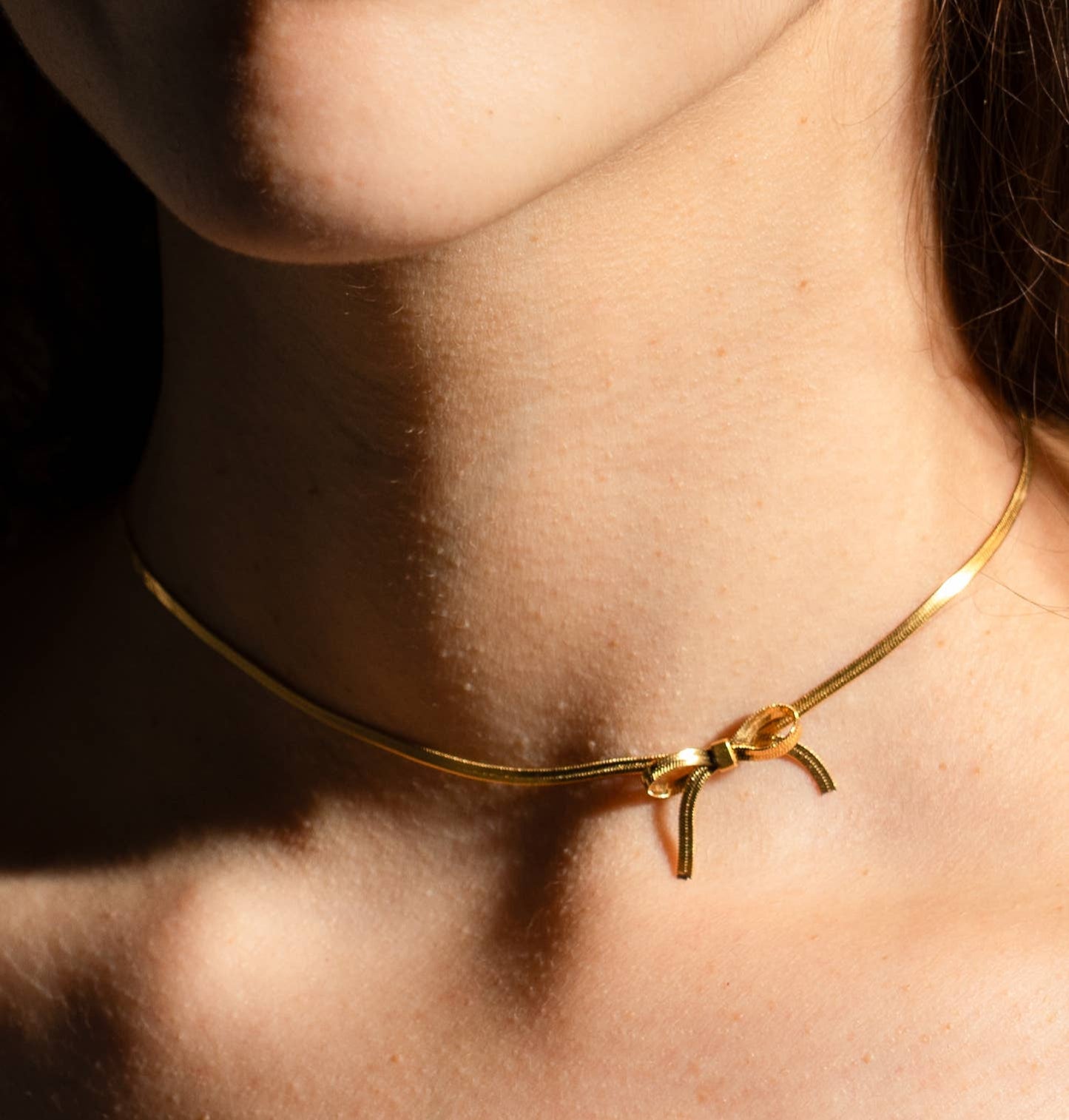 thin gold choker with a bow charm