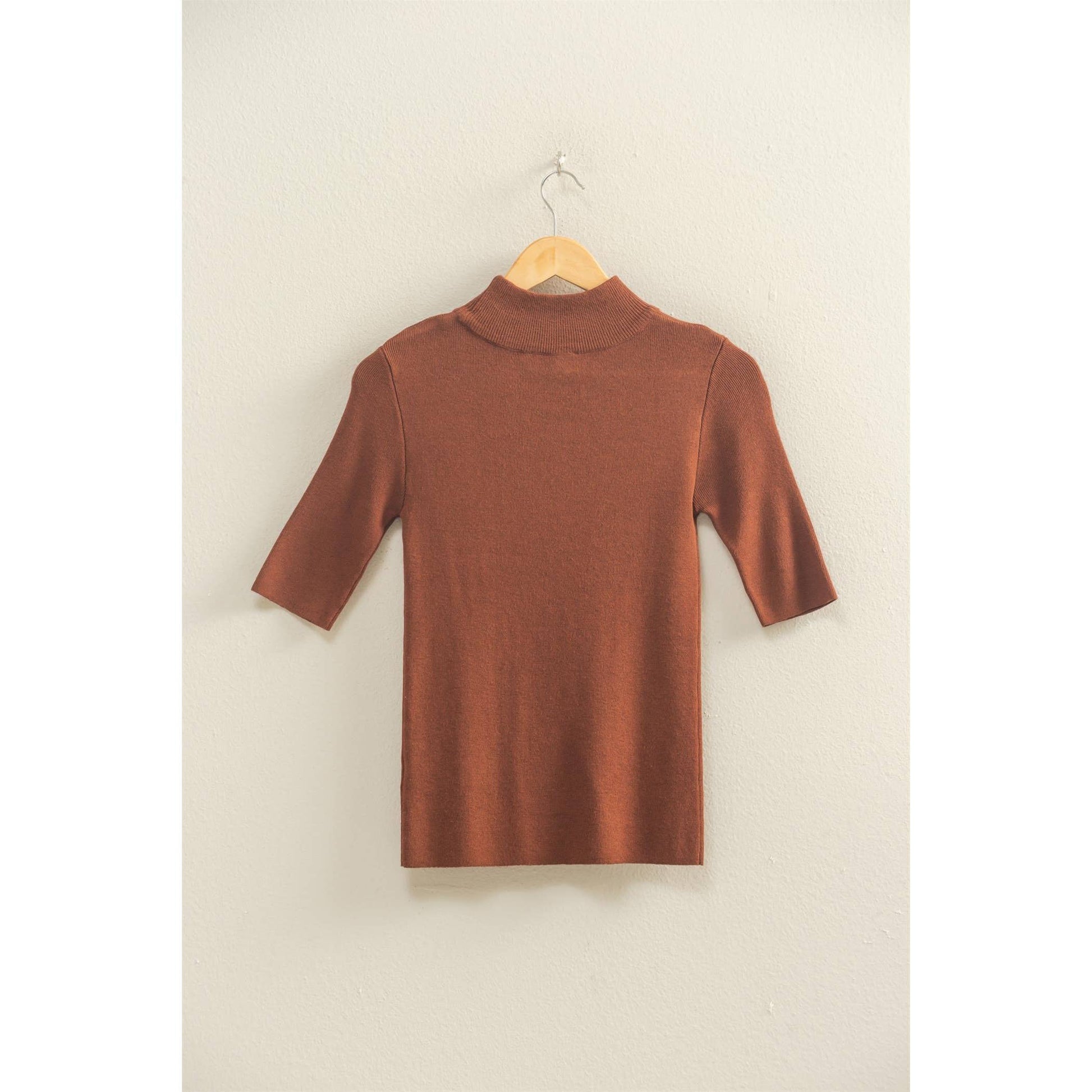 brown mock neck half sleeve top on a hanger against a beige wall