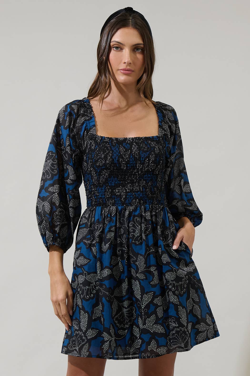 Woman wearing a black and blue patterned dress on a white background