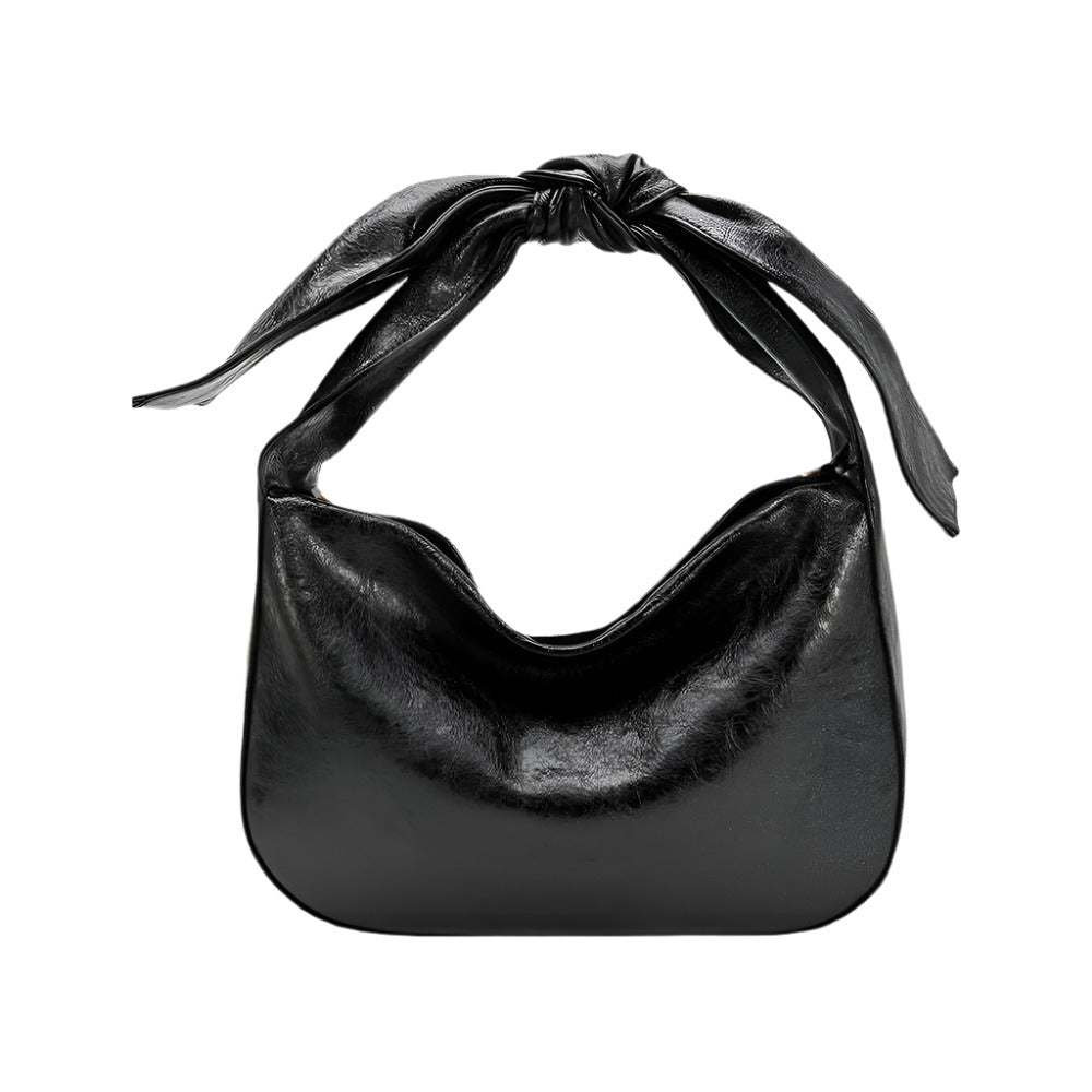 Black handbag with a bow strap on a white background