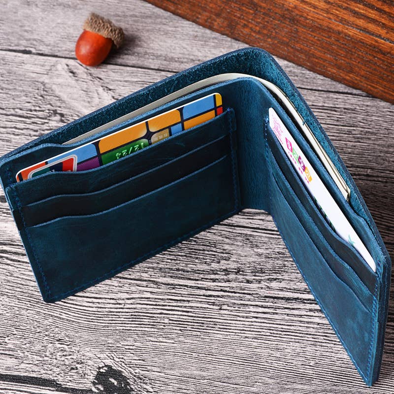 blue leather wallet opened with cards and cash inside, against wood background with an acorn beside it