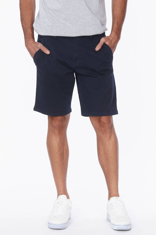 Male model wearing navy shorts with a grey tee and white sneakers.