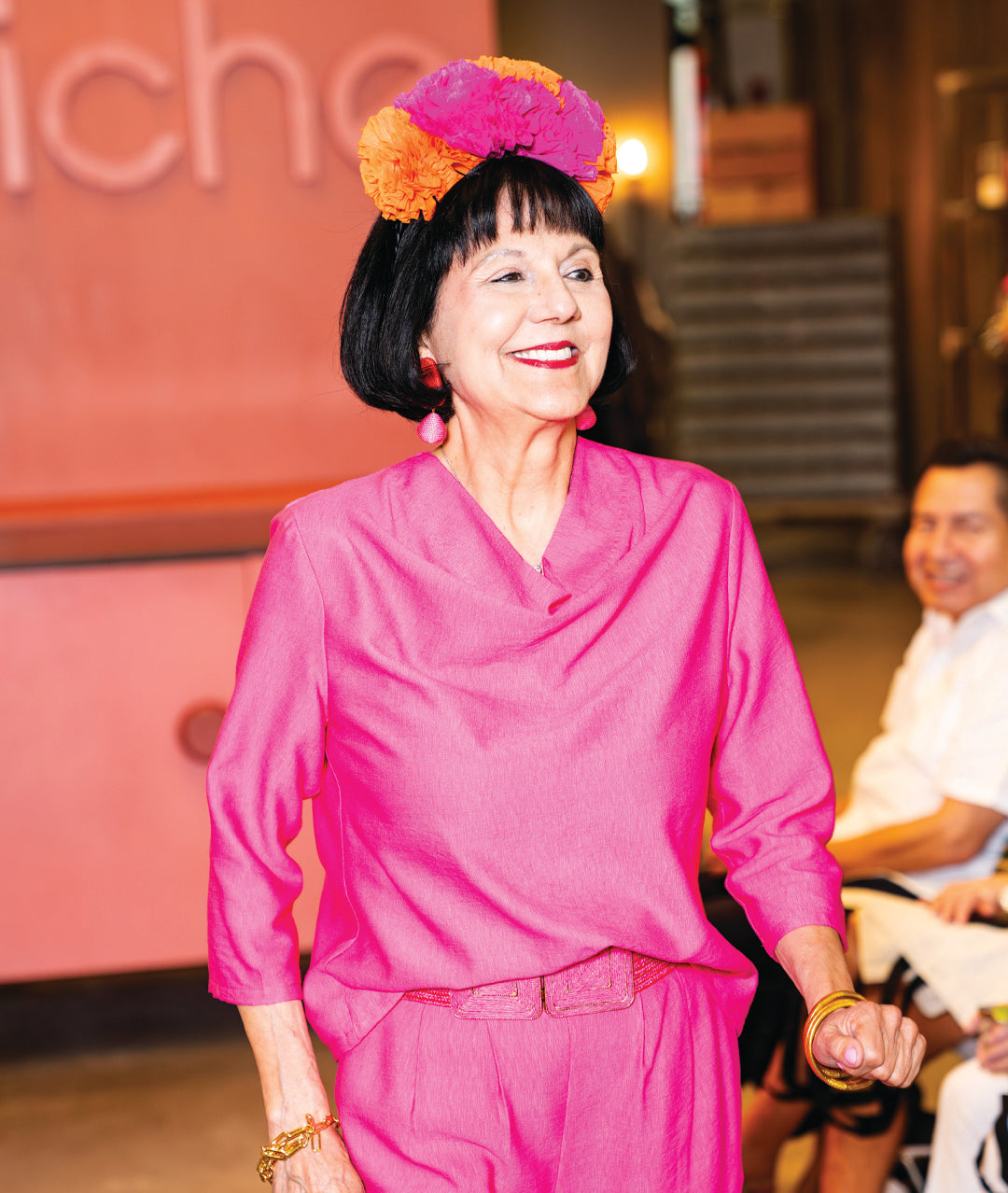 model in a hot pink pullover top with 3/4 sleeves and a cowl neckline, worn with a matching pant and belt