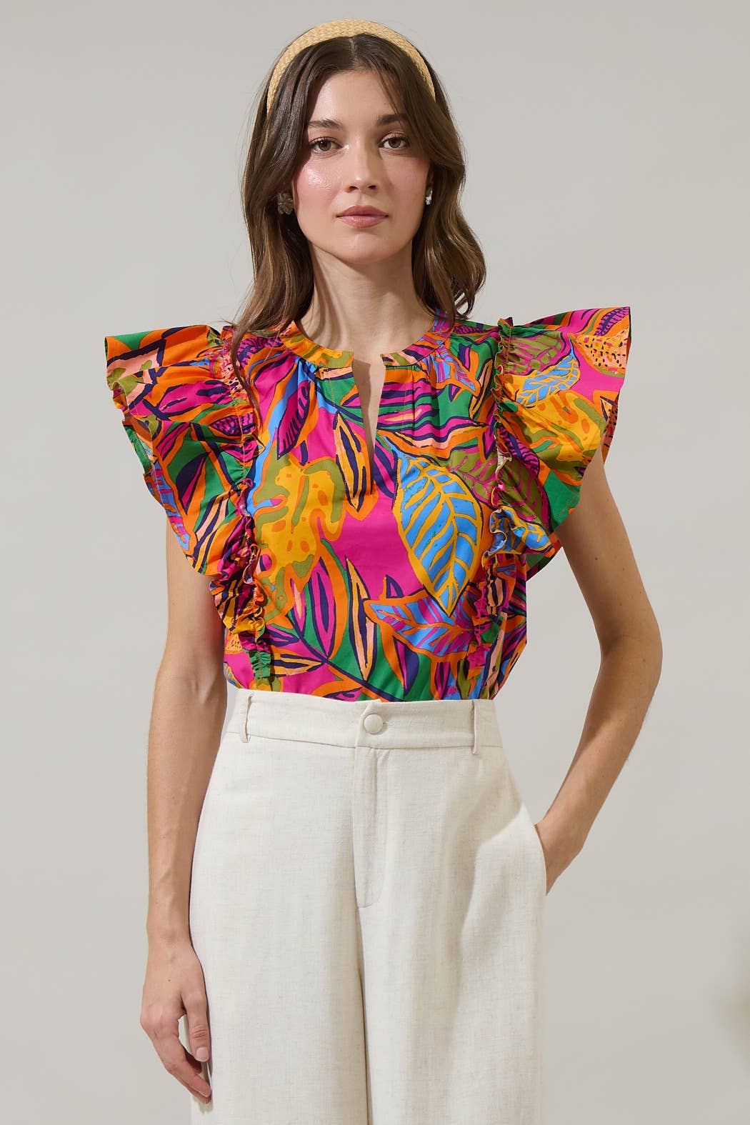 model in a multi color tropical print blouse with a white pant
