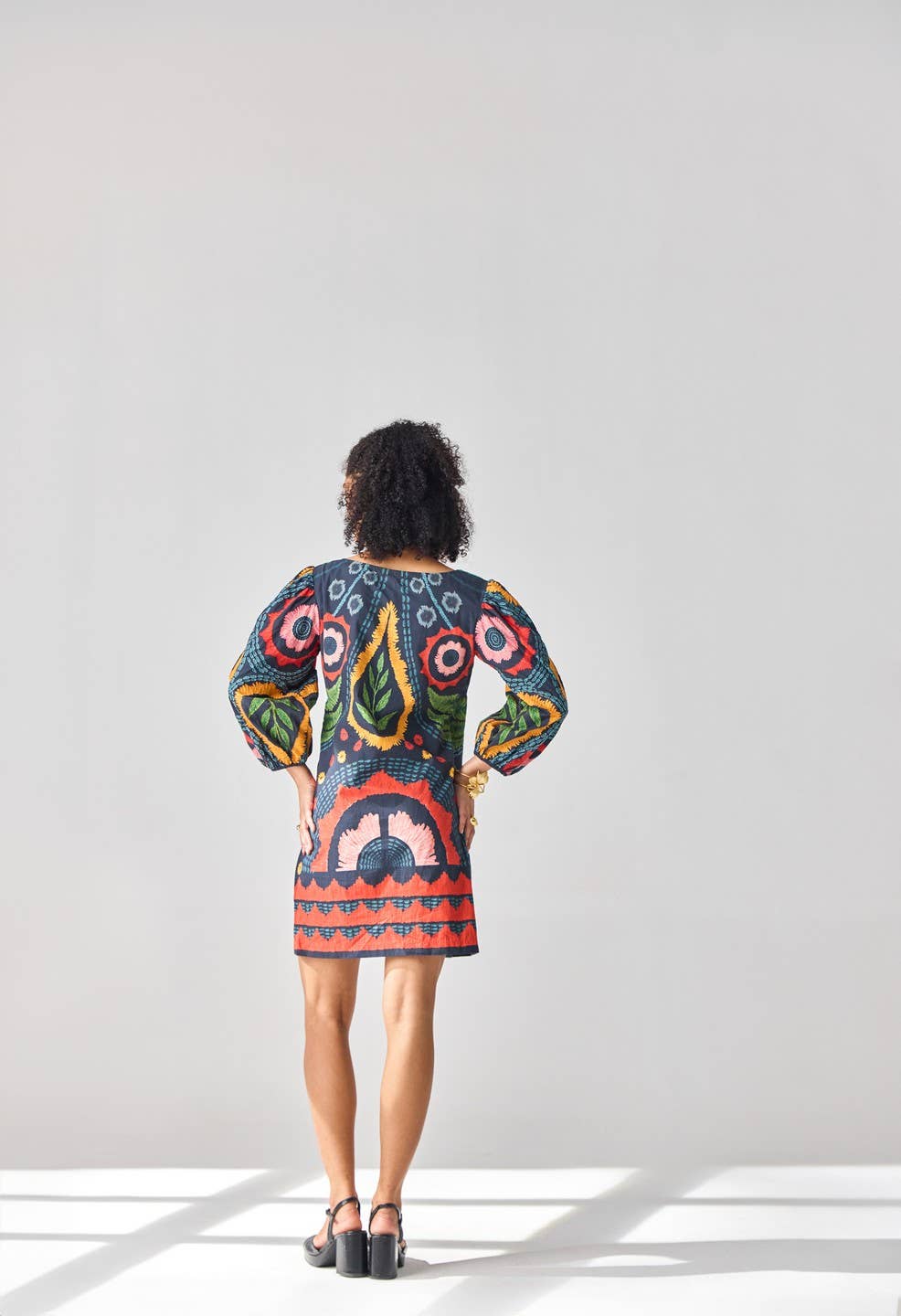 Woman wearing a colorful patterned dress on a white background
