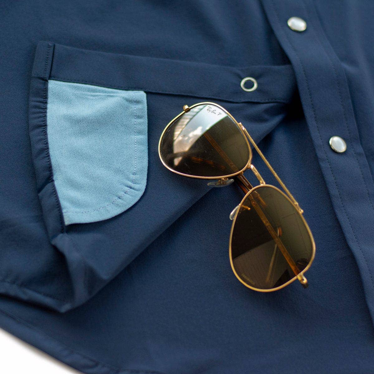 Gold sunglasses on a navy blue jacket with a light blue pocket