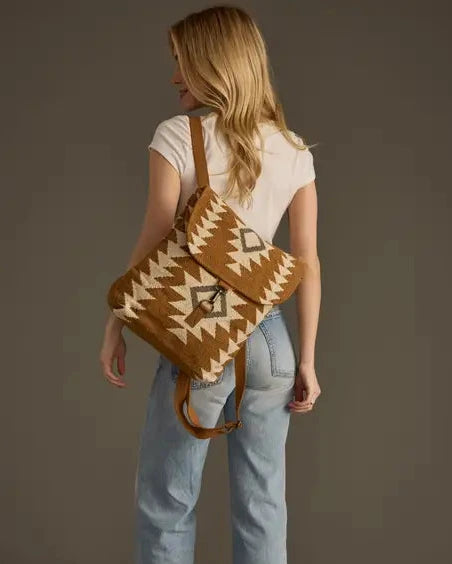Woman carrying a patterned bag over her shoulder against a plain background