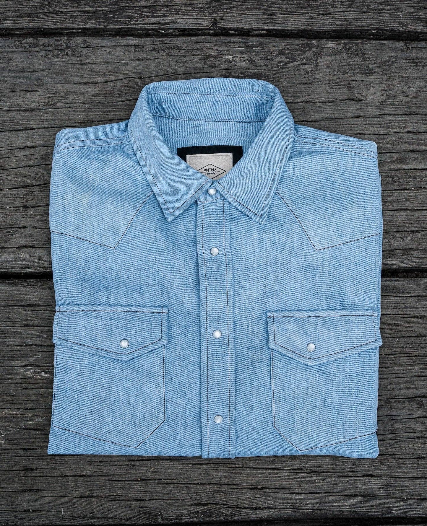 Folded light blue denim shirt on a wooden surface