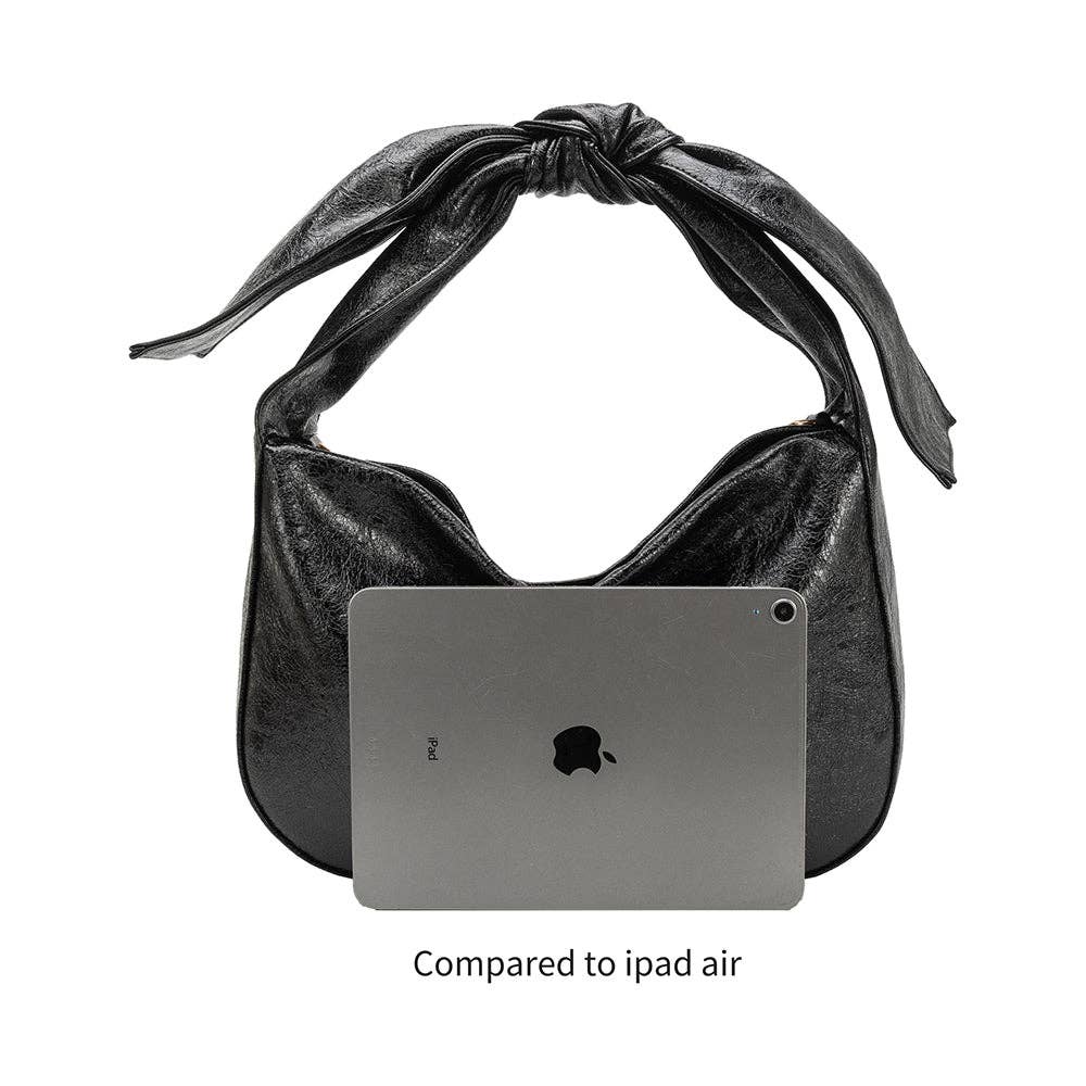 Black handbag with a knotted design holding an iPad Air on a white background