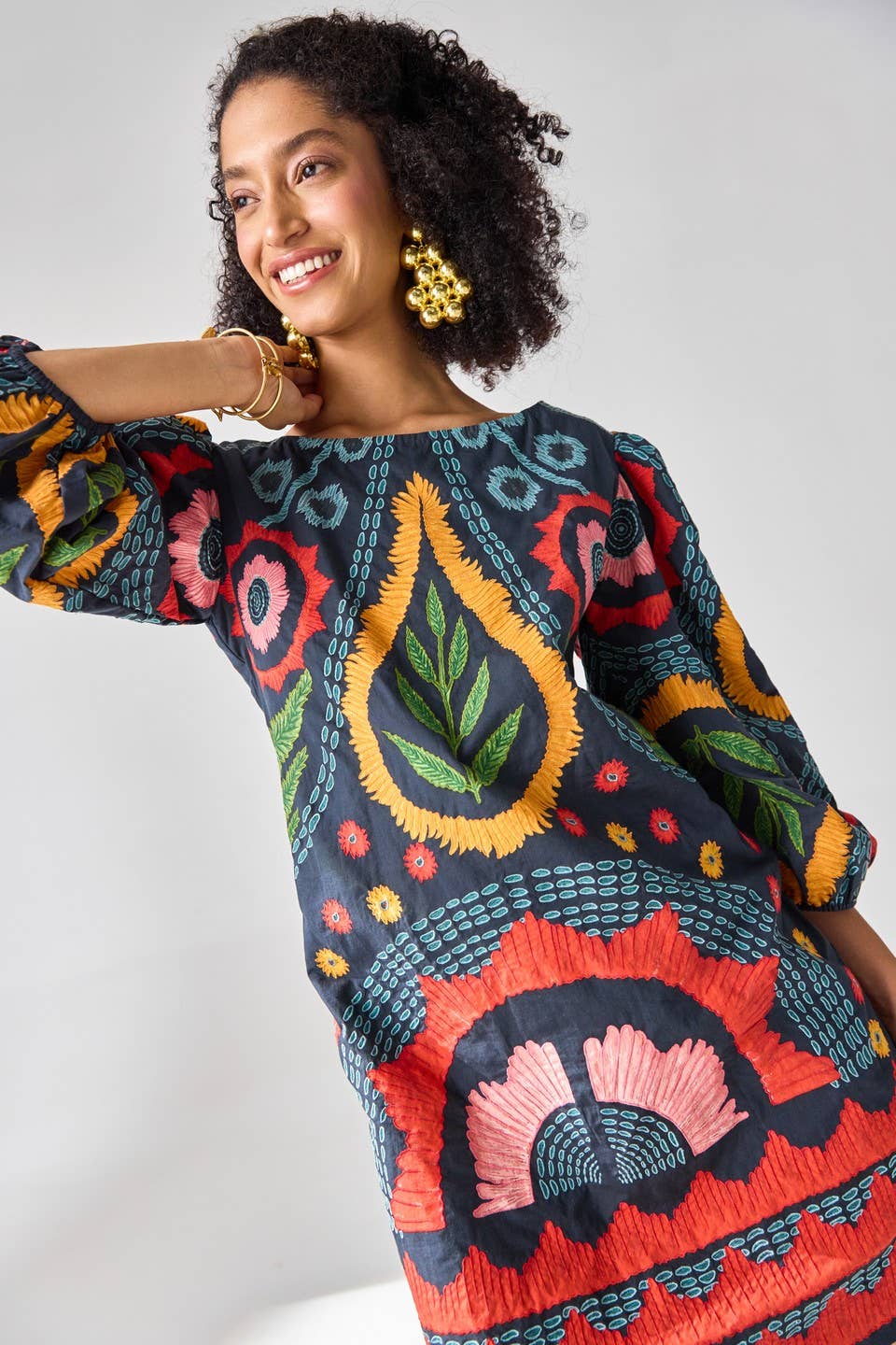 Woman wearing a colorful patterned dress against a white background