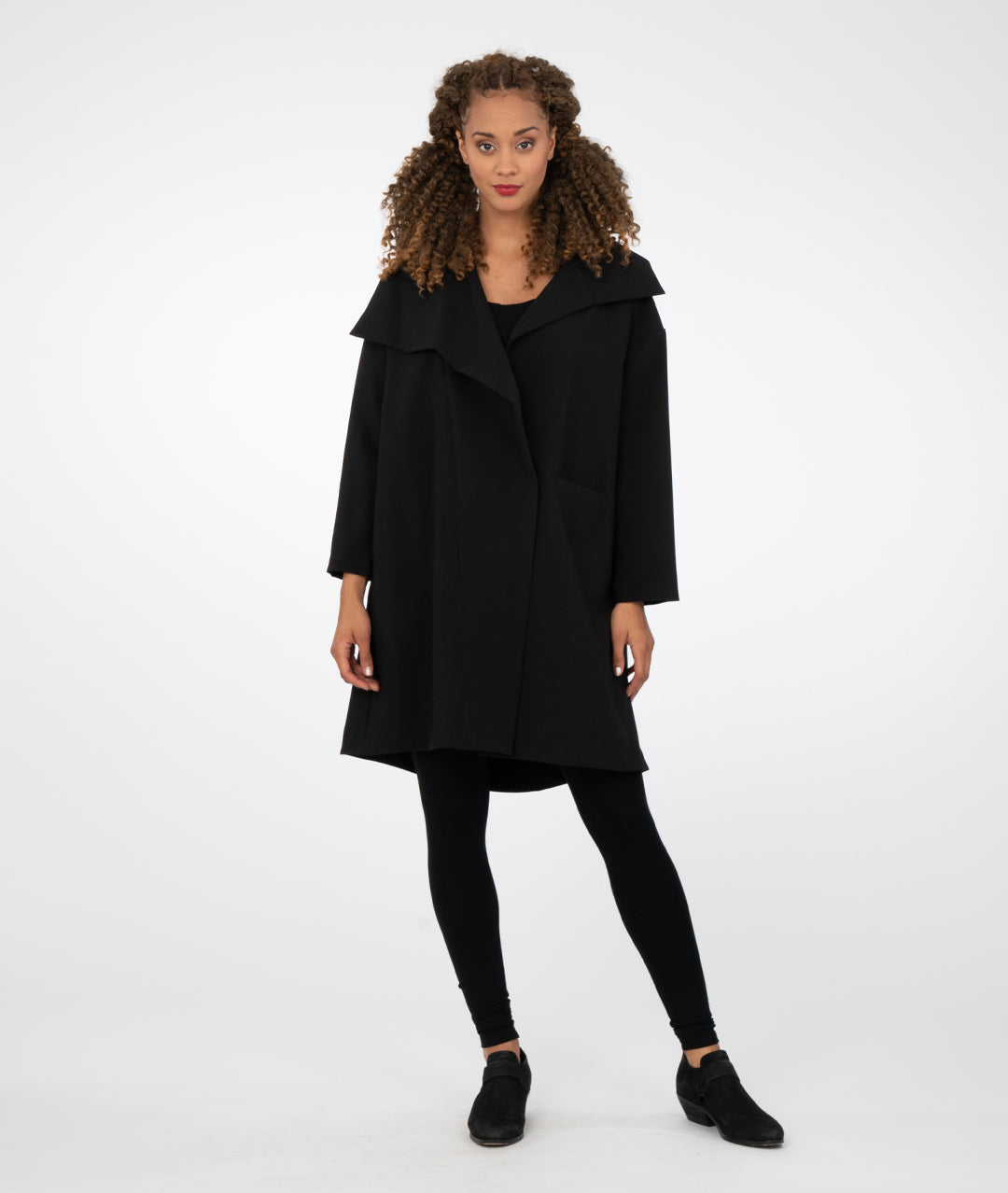 model in black leggings with a black asymmetrical jacket with a large collar