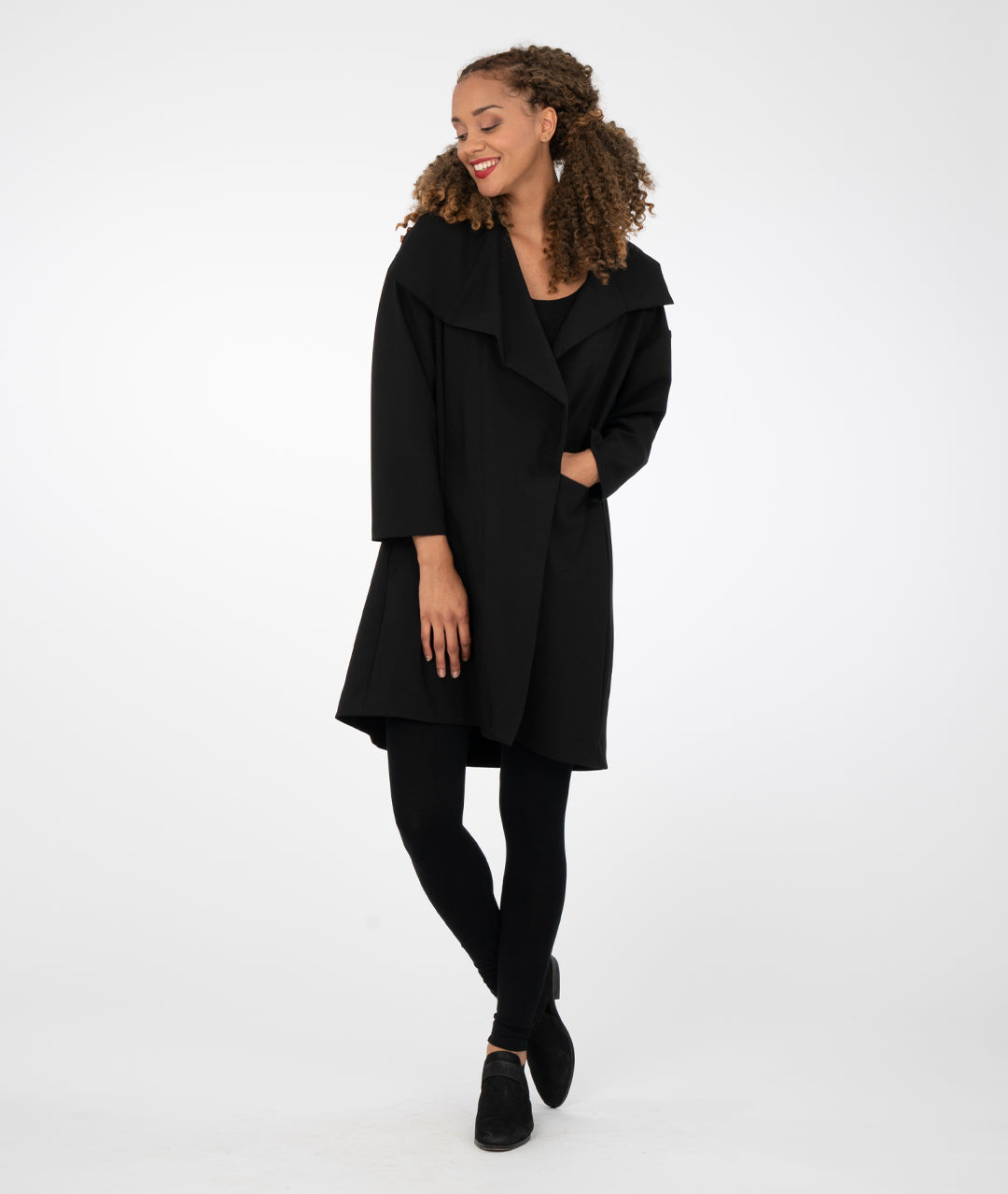 model in black leggings with a black asymmetrical jacket with a large collar