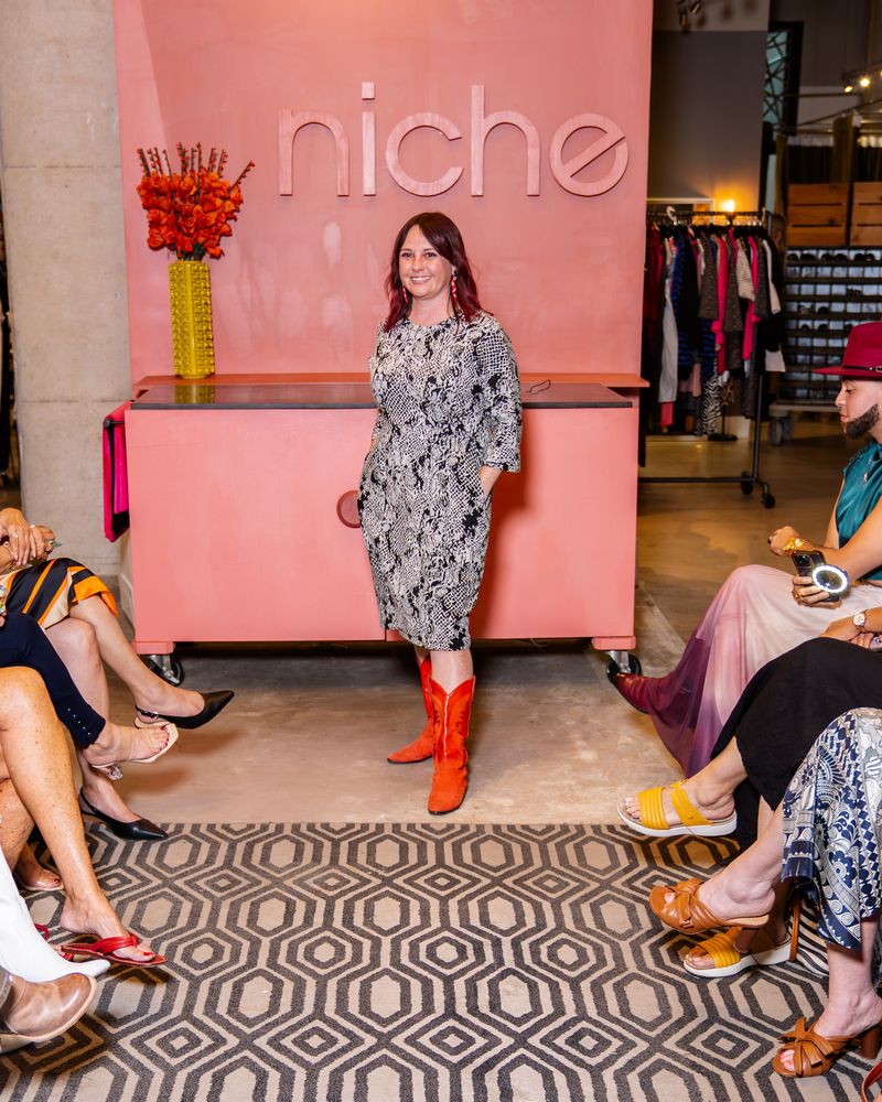 model in a patterned black and white dress and red boots walking down runway