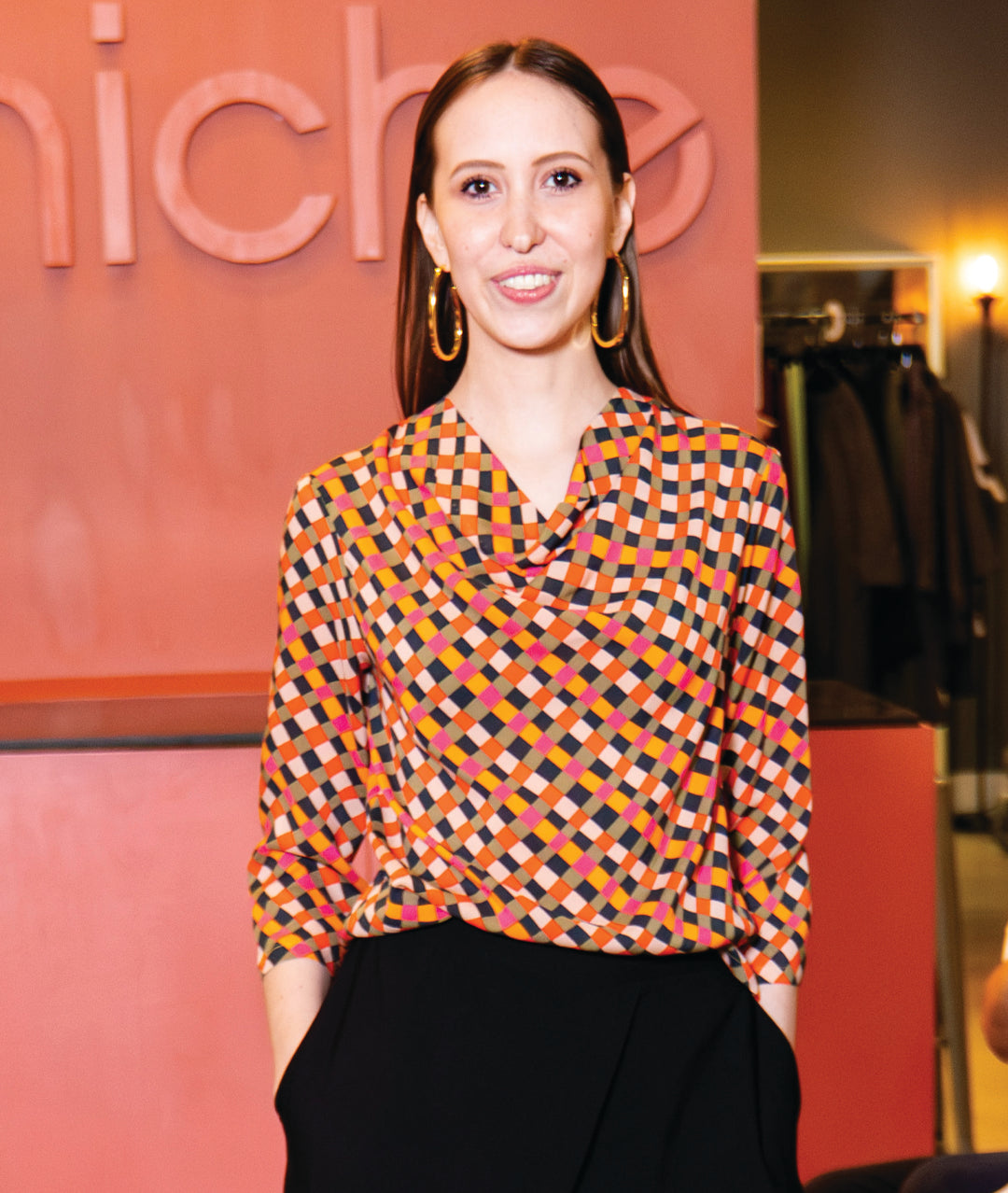 model in a black pant with a multi color harlequin print cowl top with a 3/4 sleeve
