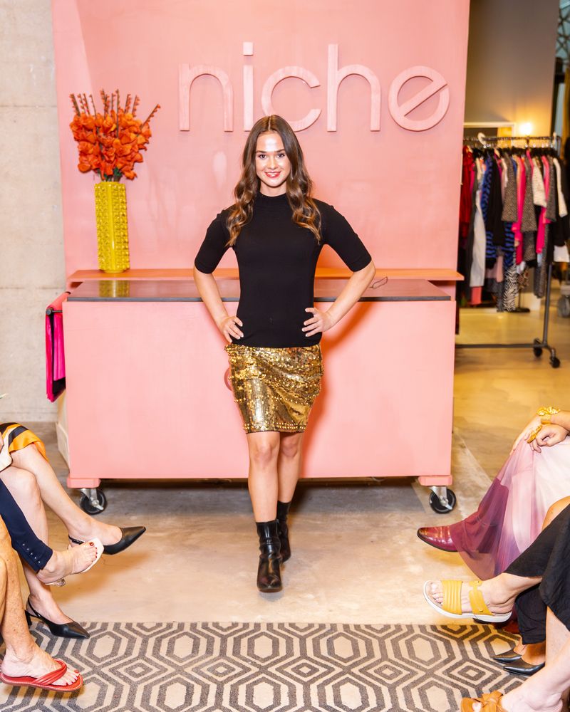 model in a gold sequin skirt and black top walking down runway