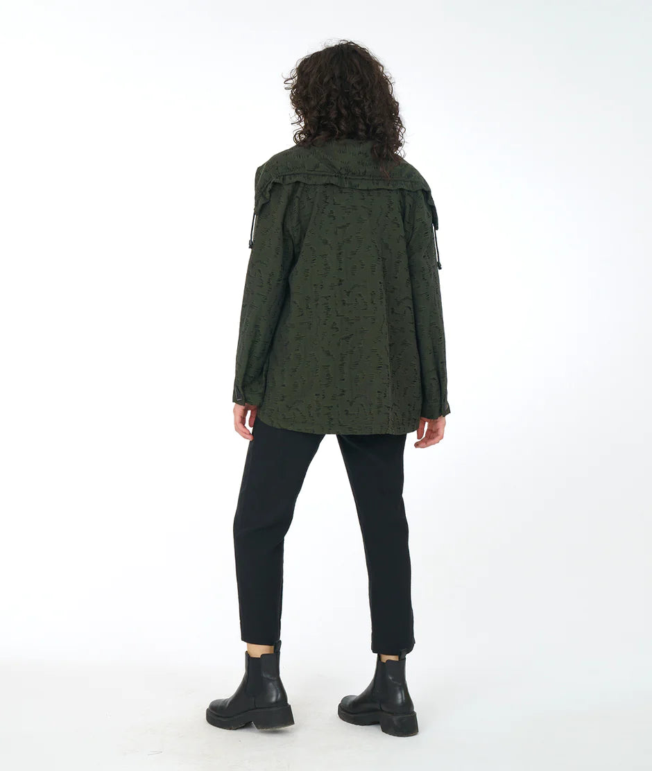 back view of model wearing an olive green jacket and black pants