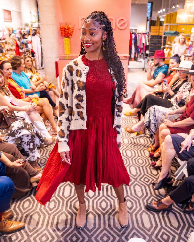 model in a red dress and leopard print cardigan walking down runway