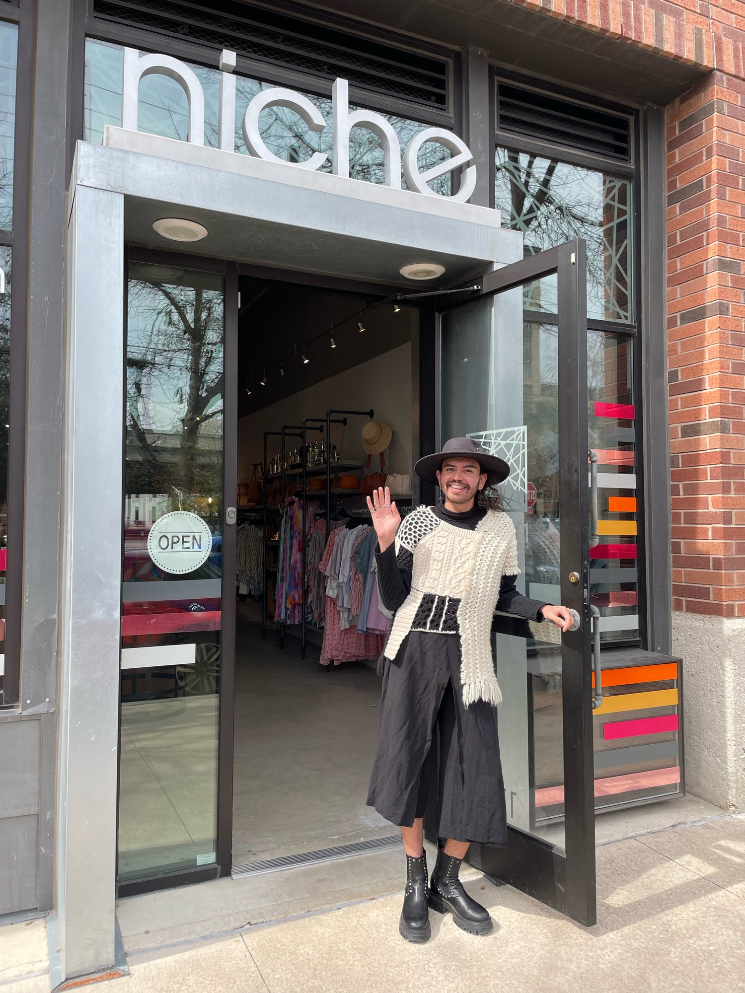 person standing in doorway of store waving