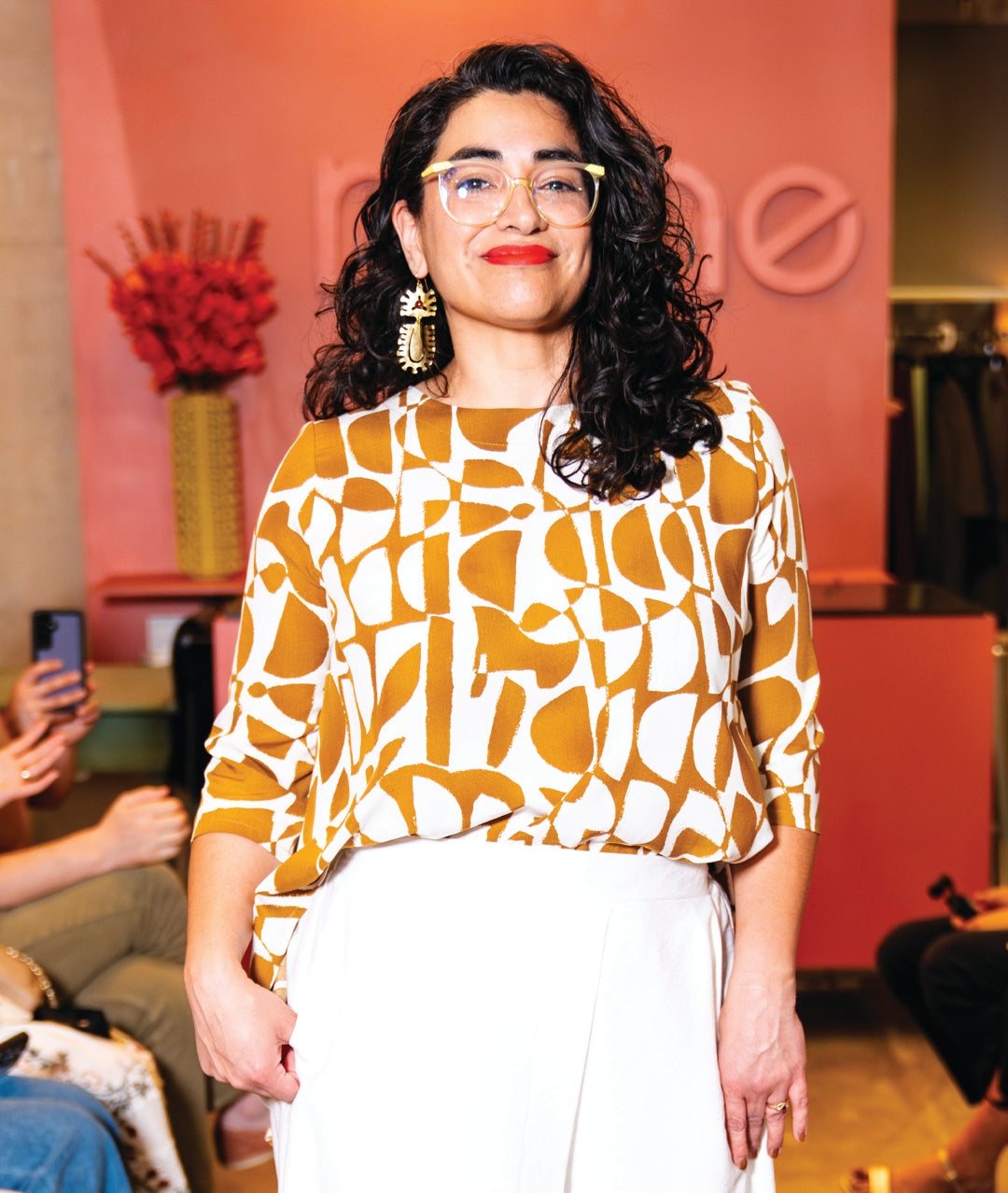 model in a white pant with a white and brown mod print pull over top with a high-low hem, 3/4 sleeves and a full bodied back