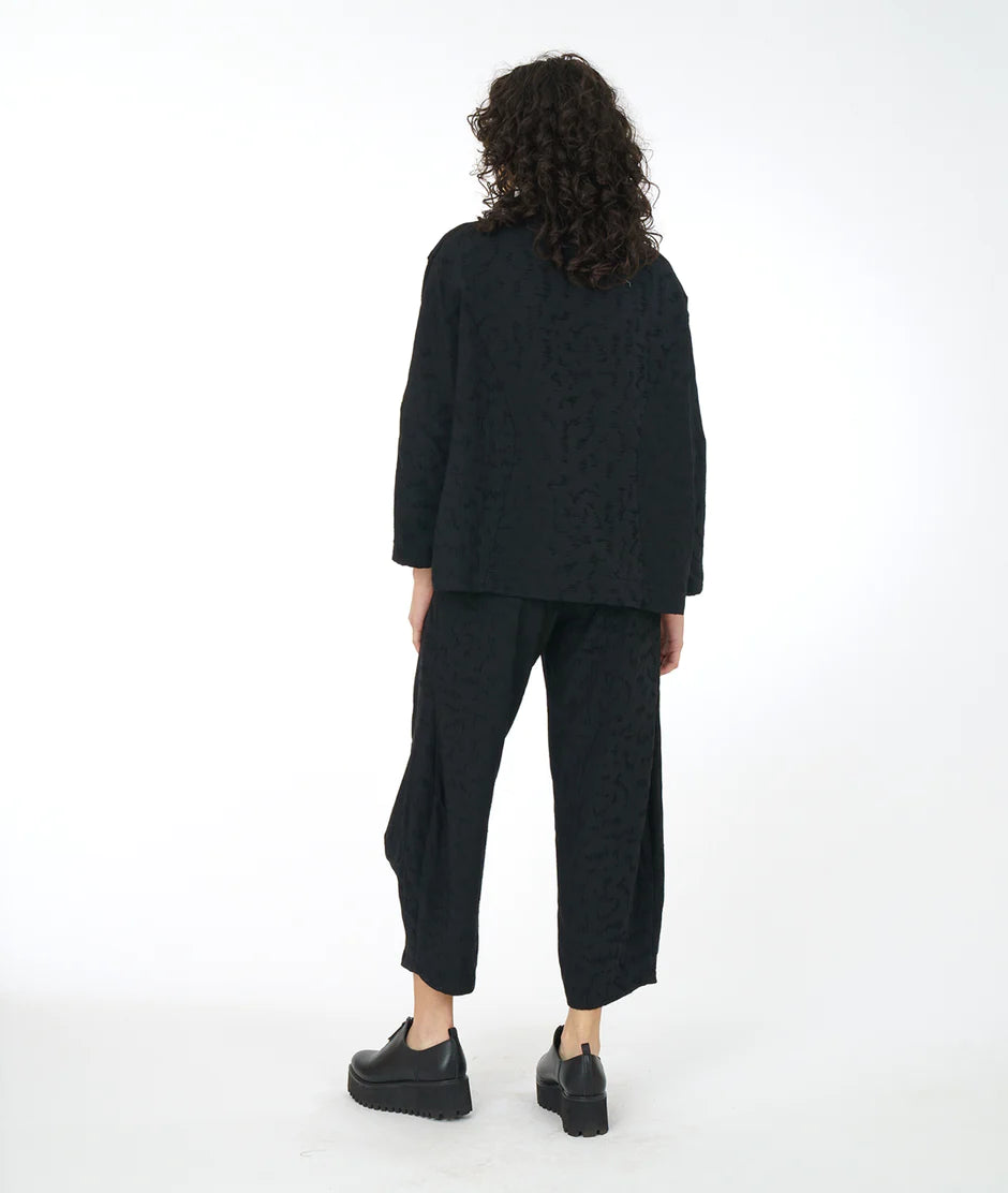 back view of a model wearing an all black outfit with a white backdrop