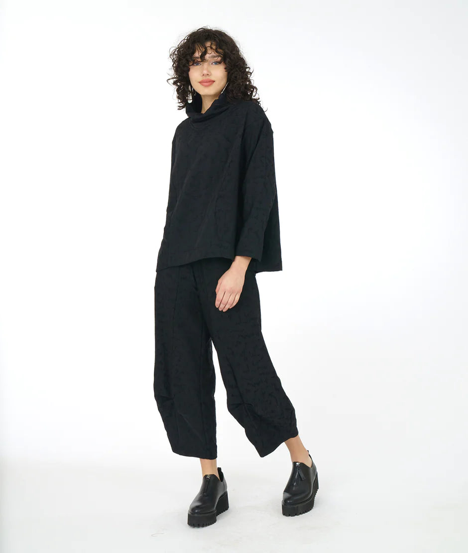 model is wearing an all black outfit with a white backdrop