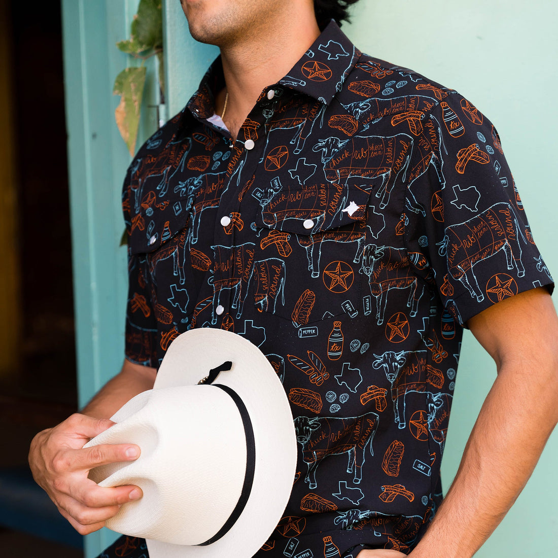Person wearing a patterned shirt holding a white hat against a light blue background