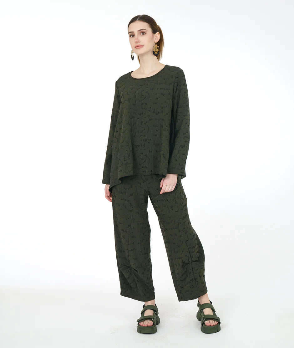 model is wearing an olive green monochrome outfit against a white backdrop