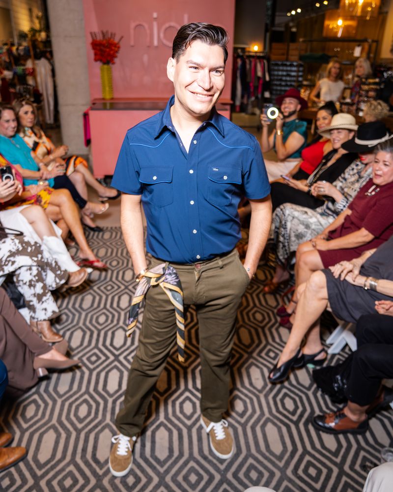 model in a blue shirt and green pants walking down a runway