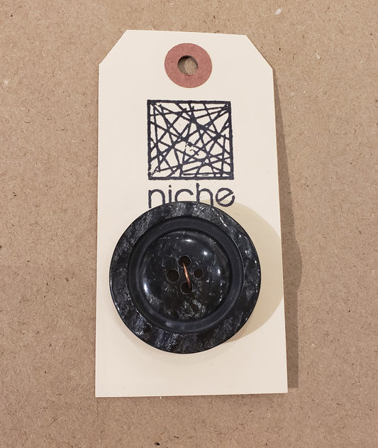 black marble button on a Niche card