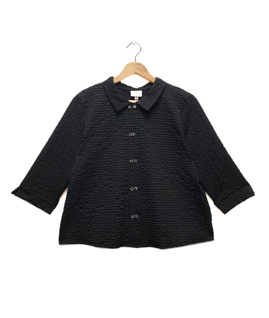 black textured button up blouse on a hanger and white background