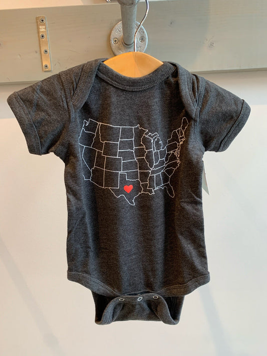 a dark grey baby onesie with a drawing of  the united states with a heart in the center of texas