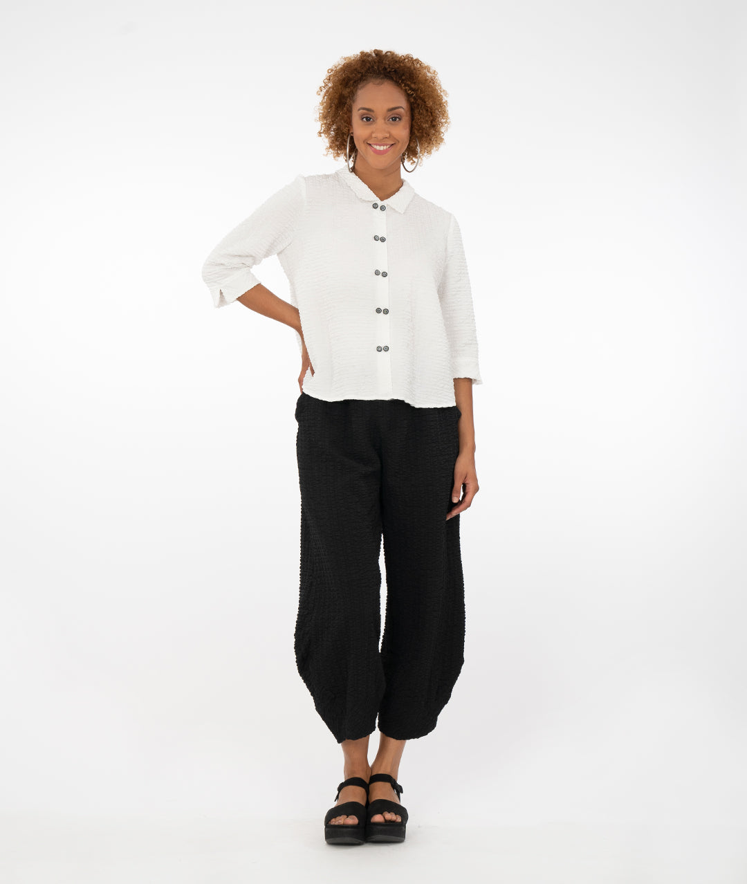 model with a white button up shirt with a black pant in front of a white back ground