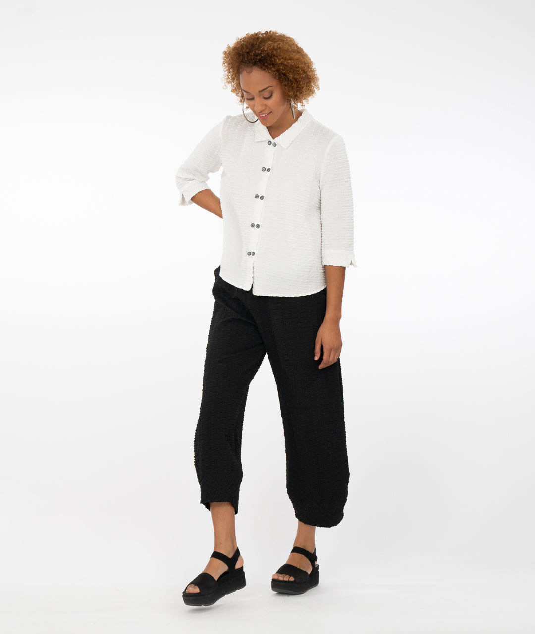 model with a white button up shirt with a black pant in front of a white back ground