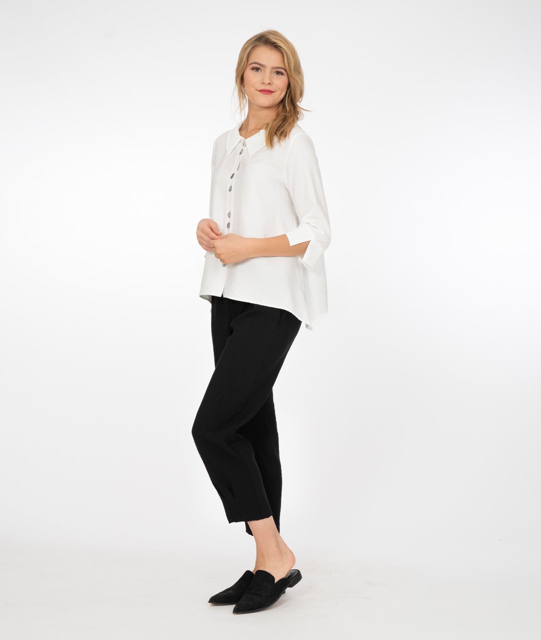 model in a white button up jacket with a collar and splits at the cuffs of the sleeves. Wearing black pants and shoes, standing in front of a white background
