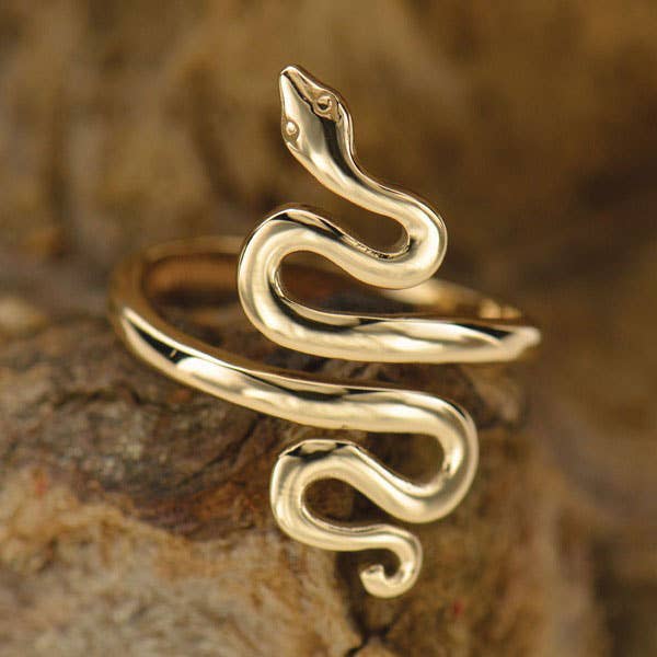 Close up of coiled snake ring in bronze. Ring is open in the center. Against a dark caramel texture background